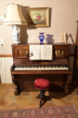 un piano dans un coin de la pièce, avec un tabouret rouge