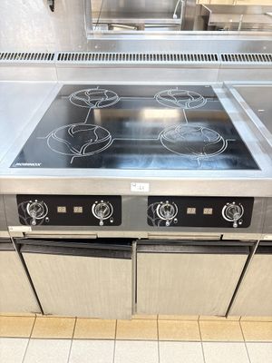 stainless steel stove top with four burners in a commercial kitchen