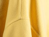the back of a yellow coat hanging on a hanger