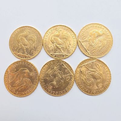 six types différents de pièces d'or posées sur une surface blanche