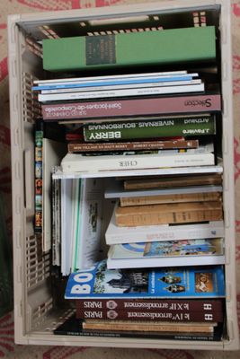 une caisse en bois remplie de livres, posée sur un lit