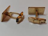 two pairs of gold cufflinks with black stones on them