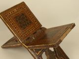 a small wooden folding chair with a decorative design on it