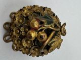 a gold brooch with a bird and flowers on it