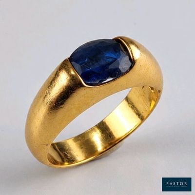 gros plan d'une bague en or avec une pierre bleue