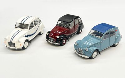 trois petites voitures sont alignées sur une surface blanche