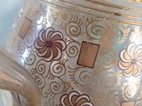 a silver vase with gold designs on it sitting on a table
