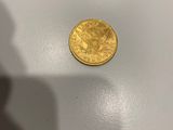 une pièce d'or posée sur une table, à côté de l'ombre d'une personne