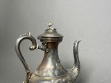 an antique silver tea pot with a handle on a gray background