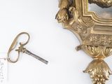 a gold clock and a key on a white table