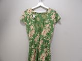 green floral dress hanging on a hanger against a white wall