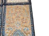 a close up of a blue and gold oriental rug on a white surface