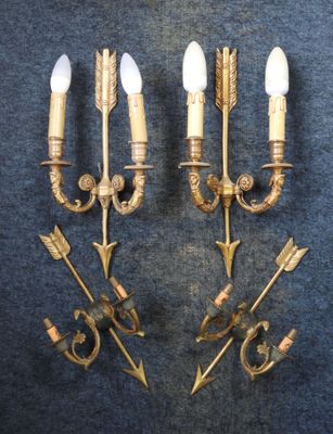 two brass wall sconces with arrows on them on a blue background