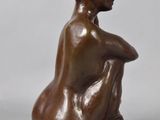 bronze sculpture of a woman sitting on her knees with her hands on her knees