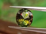 un gros plan d'un diamant vert et jaune tenu par une paire de pinces