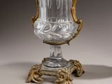 a glass vase that is on a stand on a table