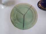 a green plate with a clock on it next to a vase