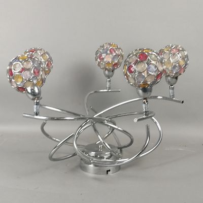 un bougeoir en argent surmonté de trois boules en verre