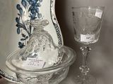 a glass bowl with a lid and a wine glass on a table