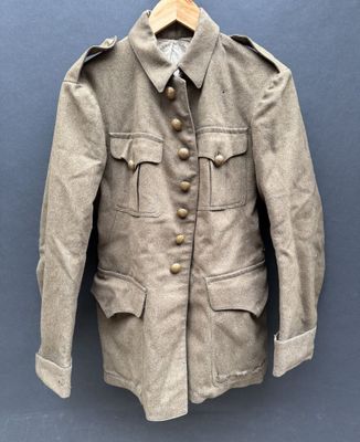 une vieille veste militaire accrochée au mur à un cintre en bois