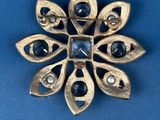 an image of a gold broochle with blue stones on it