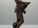 bronze statue of a boy holding a bird on a pedestal