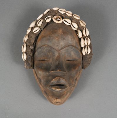 an image of a wooden mask with shells on its head