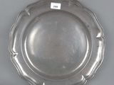 assiette en argent plaqué, à bord festonné, sur fond gris, avec une étiquette blanche