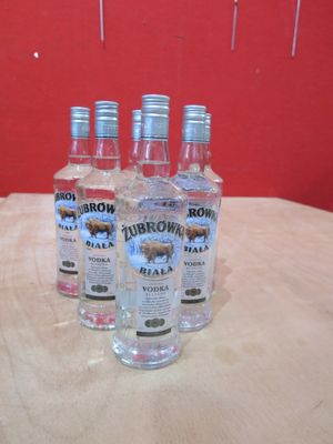 quatre bouteilles de vodka posées sur une table, avec un mur rouge en arrière-plan