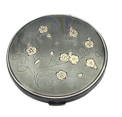 a small silver pill case with flowers on it