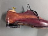 purple and brown shoes hanging on a wall on a gray surface