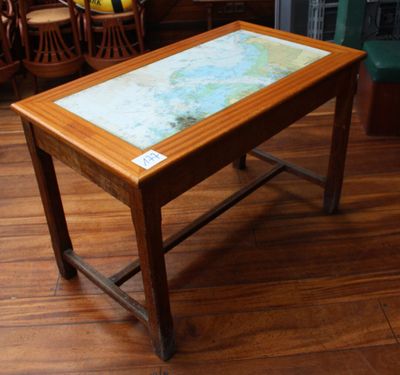 une petite table avec un plateau en verre posée sur un parquet