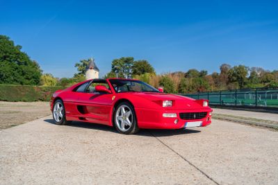 a red sports car parked in a parking lot next to a tennis court