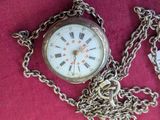 a pocket watch with a chain around it on a red cloth