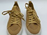 a pair of tan sneakers with white soles on a white surface