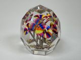 un vase en verre posé sur une table, dans lequel se trouvent des fleurs colorées