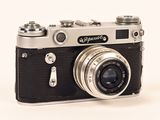 a black and silver camera sitting on a white surface