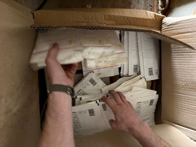 a man that is holding some mail in a box