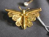 a gold butterfly brooch with a tag attached to it