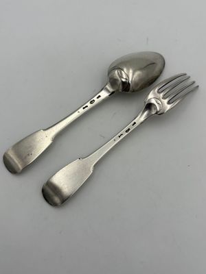 deux cuillères et une fourchette en argent sur une surface blanche