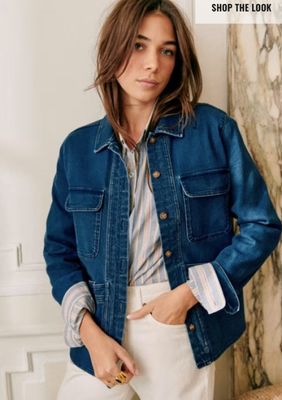 the woman is wearing a denim jacket and white pants
