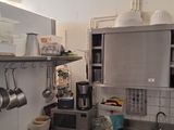 une cuisine avec des placards en inox et des casseroles et poêles accrochées au mur