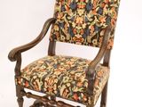 une vieille chaise avec un dossier et des accoudoirs tapissés de fleurs