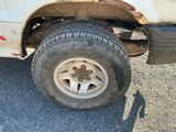 un camion blanc avec un pneu crevé, garé sur le bord de la route