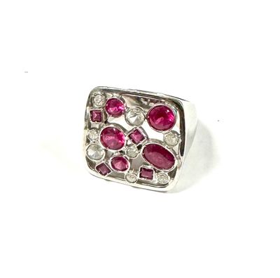 a close up of a ring with pink stones on a white surface