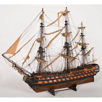une vieille maquette en bois représentant un voilier, posée sur un socle