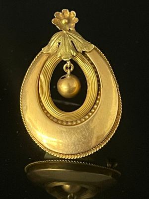 an image of a gold pendant with a pearl hanging from it ' s center