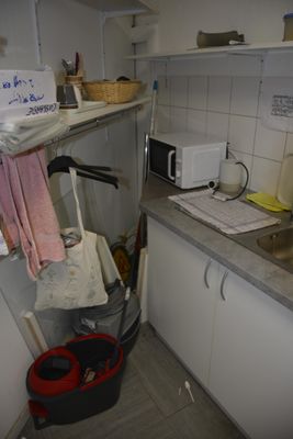a small kitchen with a sink and a trash can in it