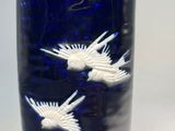 a blue vase with white birds on it sitting on a table
