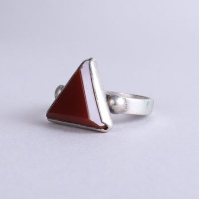 a close up of a silver ring with a red stone in it